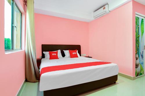 a bedroom with pink walls and a bed with red pillows at OYO 89387 Sun Keerana Hotel in Klang