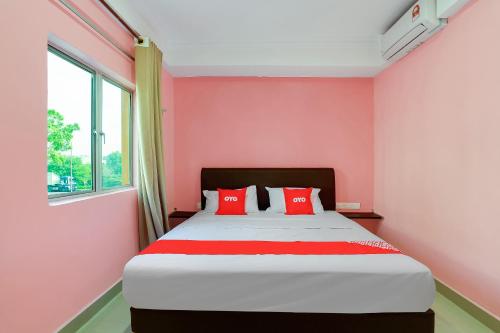 a bedroom with pink walls and a bed with red pillows at OYO 89387 Sun Keerana Hotel in Klang
