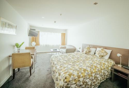 a hotel room with a bed and a living room at Airport Delta Motel in Christchurch