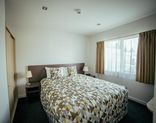 a bedroom with a large bed and a window at Airport Delta Motel in Christchurch