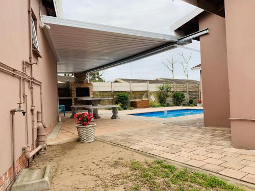 um pátio com toldo ao lado de uma casa com piscina em Sivande B&B em Richards Bay
