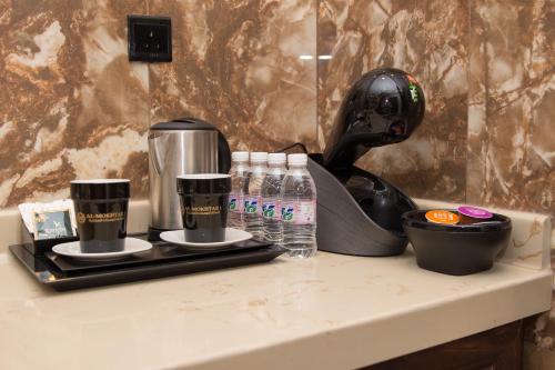 a counter with a coffee maker and bottles of water at Al Mokhtar Furnished Units in Taif