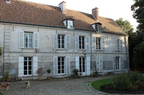 uma casa velha com janelas brancas e dois cães na frente em Chambres d'hôtes de Parseval em Senlis