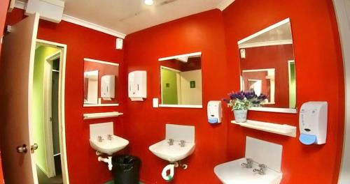 a red bathroom with two sinks and mirrors at Rotorua Downtown Backpackers in Rotorua