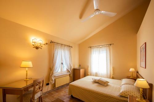 a bedroom with a bed and a desk and two windows at Il Mandorlo - Agriturismo e Azienda Agricola Ferrato in Ancona