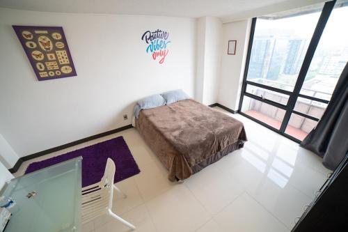a small bedroom with a bed and a window at Caravansaro Penthouse Polanco in Mexico City