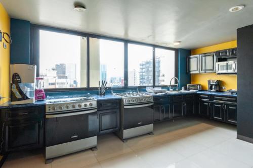 a large kitchen with black appliances and a large window at Caravansaro Penthouse Polanco in Mexico City