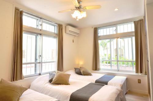 three beds in a room with large windows at Purple House in Chatan