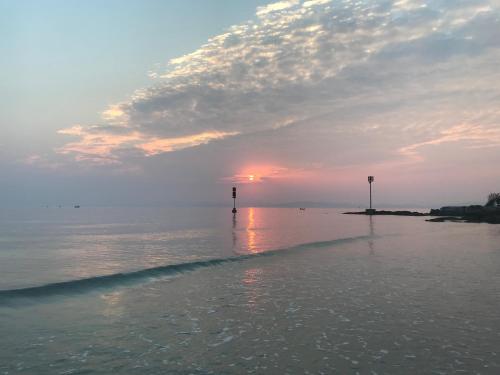 a sunset over a body of water with a lighthouse at Coto Center Homestay in Dao Co To