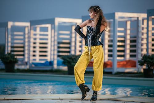 a woman in yellow pants standing next to a pool at Riviera by Queens Hotel and Resort in Gura Văii