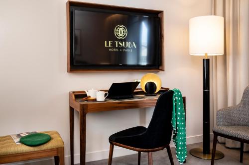 a room with a desk with a laptop and a tv at Le Tsuba Hotel in Paris