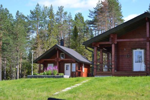 a log cabin in the woods with a grassy field at Kenttäniemi Cottages in Sonka
