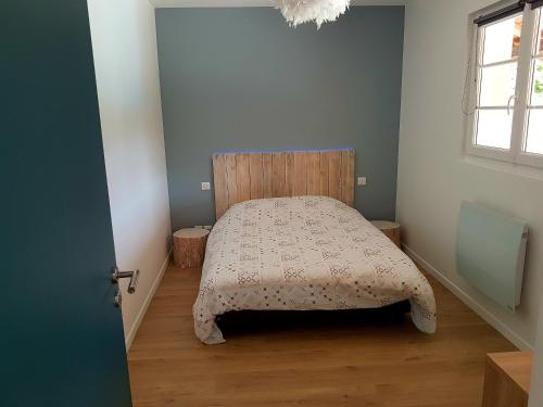 1 dormitorio con 1 cama con cabecero de madera y ventana en Dépendance au goût de vacances en Moulainville-la-Basse