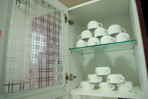 a shelf with a bunch of white cups on it at The Most Beautiful Property Of Rishikesh in Rishīkesh