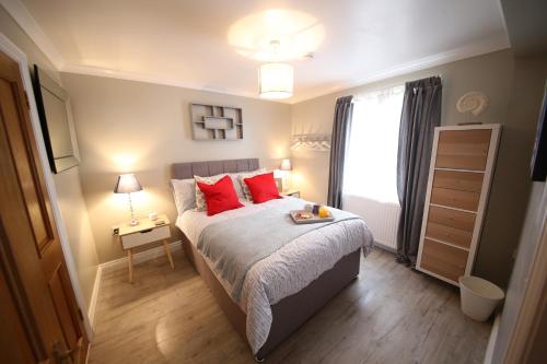 Schlafzimmer mit einem Bett mit roten Kissen und einem Fenster in der Unterkunft Number 4 in Exeter
