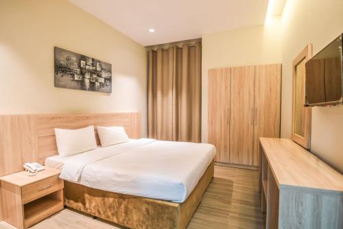 um quarto de hotel com uma cama e uma televisão de ecrã plano em Grand Flora Hotel em Salalah