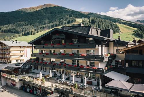 a building with flowers on the balconies and a mountain at Der Gollinger in Saalbach Hinterglemm