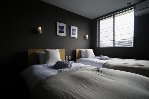 two beds in a dark room with a window at sararaso in Kanazawa