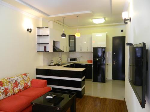 a living room with a red couch and a kitchen at Chemi Saxli Apartment in Batumi