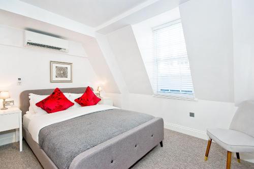 a bedroom with a bed with red pillows and a chair at Eldon Chambers Flat 2 by City Living London in London