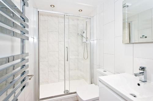 a white bathroom with a shower and a sink at Eldon Chambers Flat 2 by City Living London in London