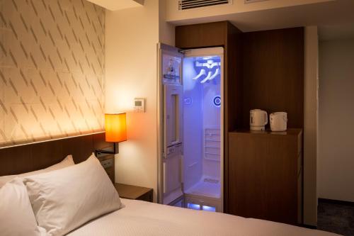 a hotel room with a bed and a shower at HOTEL FORZA HAKATAEKI CHIKUSHI-GUCHI Ⅰ in Fukuoka