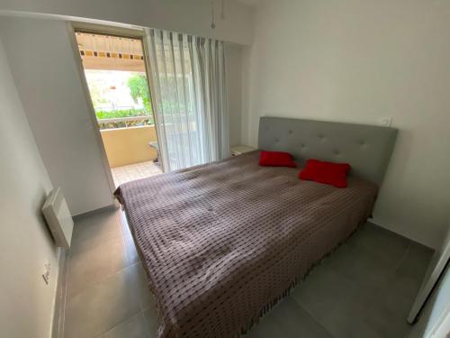 une chambre avec un lit avec deux oreillers rouges dessus dans l'établissement Antibes Juan les Pins center,1 bedroom apart, pool, à Antibes