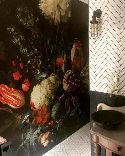 a painting of flowers on a wall in a bathroom at The Lodge Duxford in Duxford