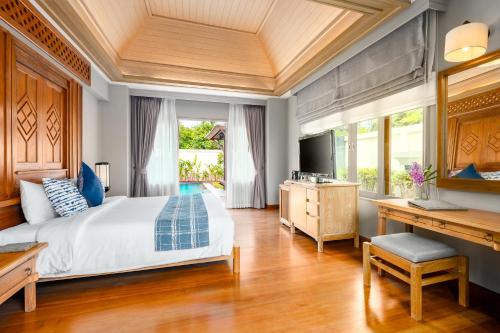 a bedroom with a bed and a desk and a television at Fair House Villas & Spa, Koh Samui in Mae Nam