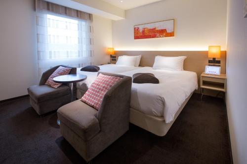a hotel room with a large bed and a chair at HOTEL FORZA HAKATAEKI CHIKUSHI-GUCHI Ⅰ in Fukuoka