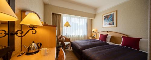ein Hotelzimmer mit 2 Betten und einem Schreibtisch in der Unterkunft Hotel Resol Sapporo Nakajima Koen in Sapporo