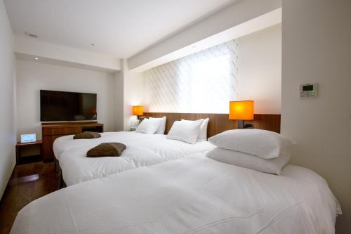 two beds in a hotel room with white sheets at HOTEL FORZA HAKATAEKI CHIKUSHI-GUCHI Ⅰ in Fukuoka