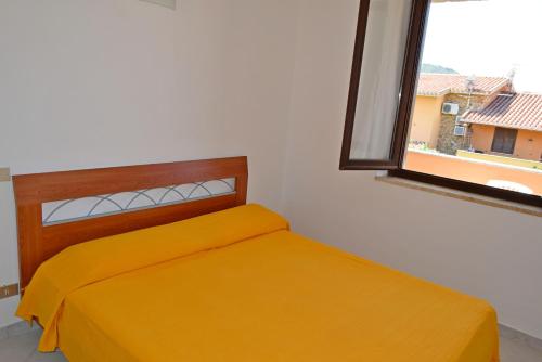 ヴィッラシミーウスにあるAppartamento Simonaのベッドルーム1室(黄色いベッド1台、窓付)