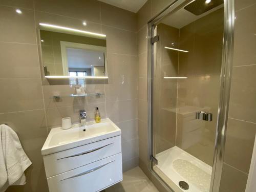 a bathroom with a shower and a sink and a mirror at No 12 Furze Croft in St Ives
