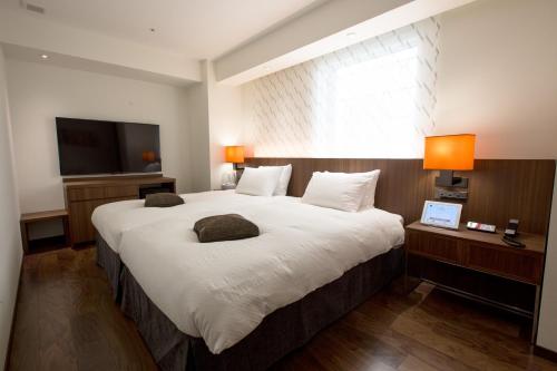 a bedroom with a large bed and a television at HOTEL FORZA HAKATAEKI CHIKUSHI-GUCHI Ⅰ in Fukuoka