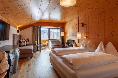 una camera con due letti in una stanza con pareti in legno di Hotel Obereggen a Obereggen