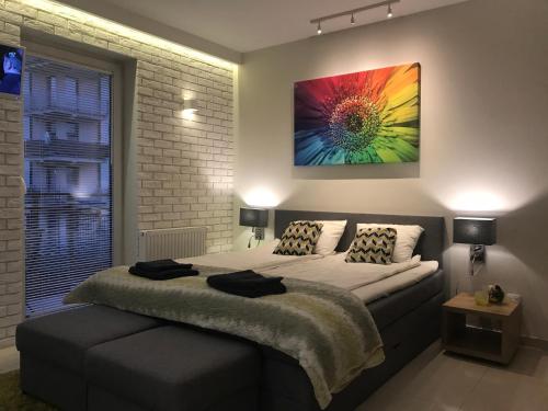 a bedroom with a bed with a colorful painting on the wall at 4UApart-Apartment studio Mohito in Świnoujście