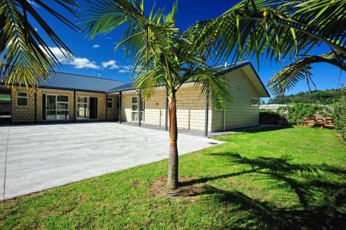 a palm tree in front of a house at Captain Cook Motor Lodge in Gisborne