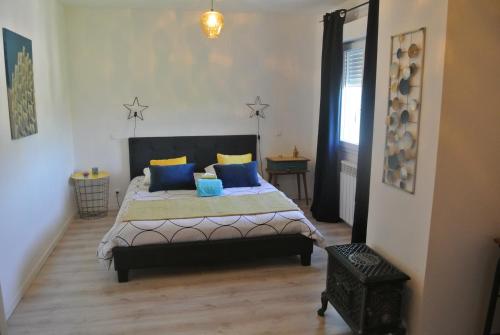 une chambre avec un lit avec des oreillers bleus et jaunes dans l'établissement Le Temps Retrouvé, à Saint-Martin-de-Valgalgues