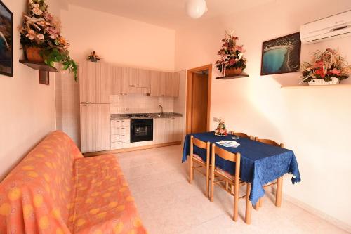 uma cozinha e sala de jantar com uma mesa e um sofá em Residenza Le Due Palme em Villasimius