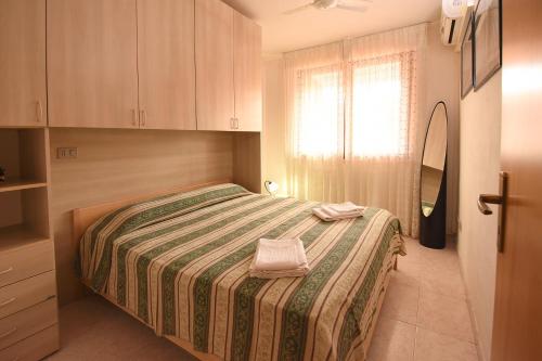 a bedroom with a bed with a green and white blanket at Residenza Le Due Palme in Villasimius