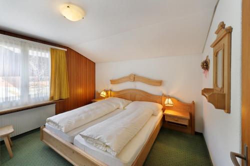 Un dormitorio con una cama grande y una ventana en Apartments Kirchbühl, en Grindelwald