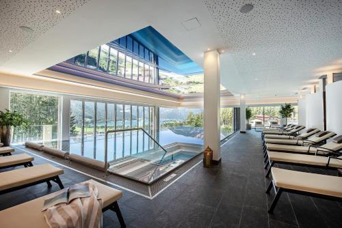 a restaurant with a pool and tables and chairs at Naturhotel Alpenblick in Maurach