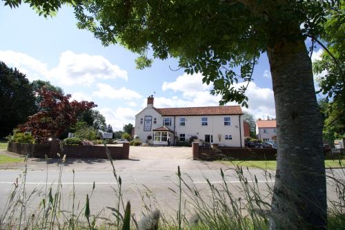 a large white house with a tree in the foreground at The Plough Inn in Marsham