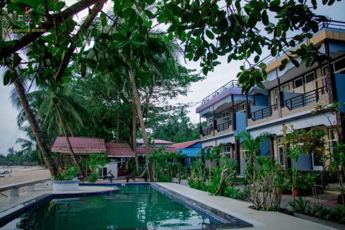 a resort with a swimming pool in front of a building at Memento Resort in Ngapali