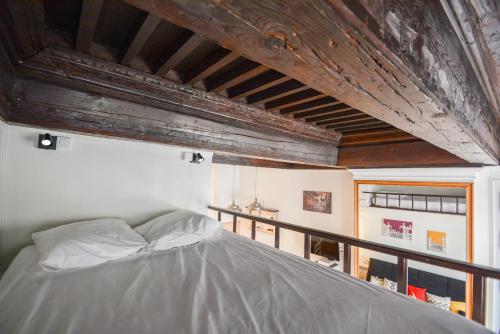 a bed in a room with a wooden ceiling at Le cocon des Deux Sirènes in Nancy