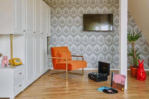 a living room with an orange chair and a tv at Max Brown Hotel Ku'damm in Berlin
