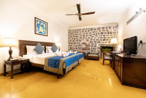 a hotel room with a bed and a television at Fort JadhavGADH -A GADH Heritage Hotel in Pune