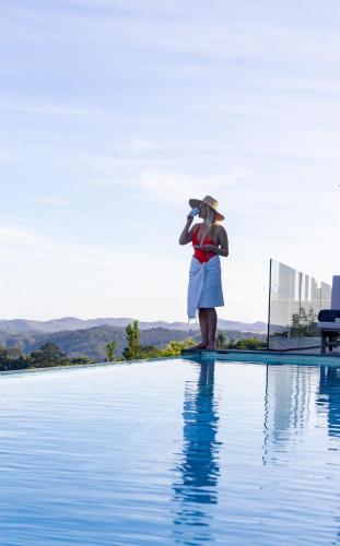 a woman standing next to a swimming pool at Collection Luxury Accomodation Simola House in Knysna