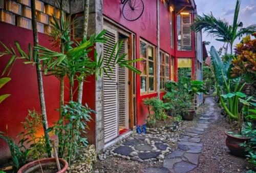 a street with plants in front of a red building at Lorong Homestay in Bantul